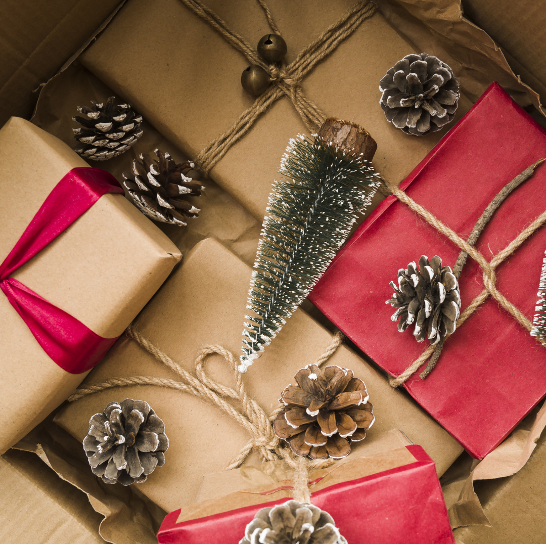 Gift boxes near fir twigs in cardboard box